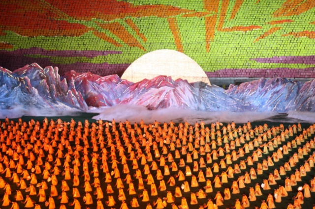 Hundreds of yellow-clad players at the Mass Games in Pyongyang, dancing before a gorgeous red and yellow image of the sun rising over Mt Paektu, composed entirely of flip-cards.